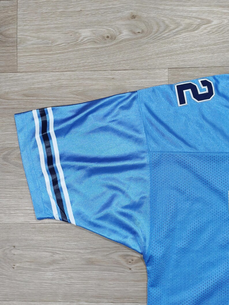 May include: Light blue mesh jersey with navy and white stripes on the sleeve. The number '2' is visible on the shoulder in navy. The jersey has a breathable, perforated texture.