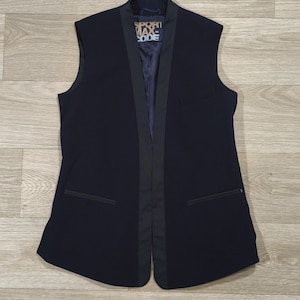 Peut inclure: Un gilet bleu marine avec une bordure noire et deux poches avant. Le gilet porte le texte "SPORT MAX CODE" sur la poitrine. Sans manches, il présente une coupe ajustée.