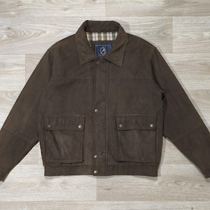 Peut inclure: Veste marron avec col et deux poches avant. La veste a une fermeture boutonnée et une doublure à carreaux visible au col. La veste est faite d'un matériau durable.