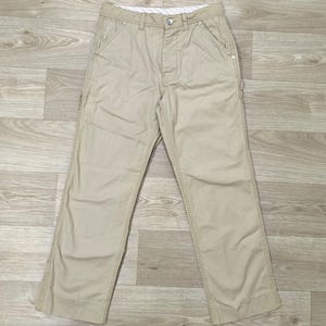 Op de afbeelding: Kleur zandkleurige broek met een rechte pijp. De broek heeft een knoopsluiting, voorzakken en een klein zijvak. Zichtbare stiksels en een stevige stof suggereren duurzaamheid. De tailleband heeft een gestreepte voering.