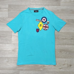 May include: A turquoise short-sleeve t-shirt with a crew neck. The shirt features several patches, including a maple leaf, a Union Jack, and the word "dsquared". The patches are in various shapes and colors.