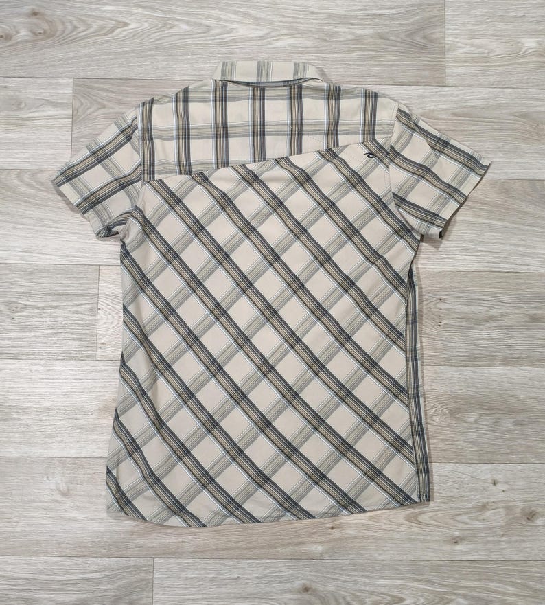May include: Short-sleeved shirt with a beige, grey, and navy blue plaid pattern. The shirt features a classic collar and a diagonal plaid design on the lower half. The fabric looks lightweight, suitable for warmer weather. Measurements are in cm.