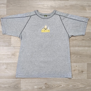 May include: Gray short-sleeved t-shirt with a crew neck and dark gray stitching. The shirt features a small graphic of a cartoon character and the word "TINTIN" in yellow letters.