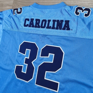 May include: Pale blue mesh jersey with the word "CAROLINA" in navy blue across the chest. The number "32" is in navy blue with a white outline. The jersey has navy blue numbers on the shoulders.
