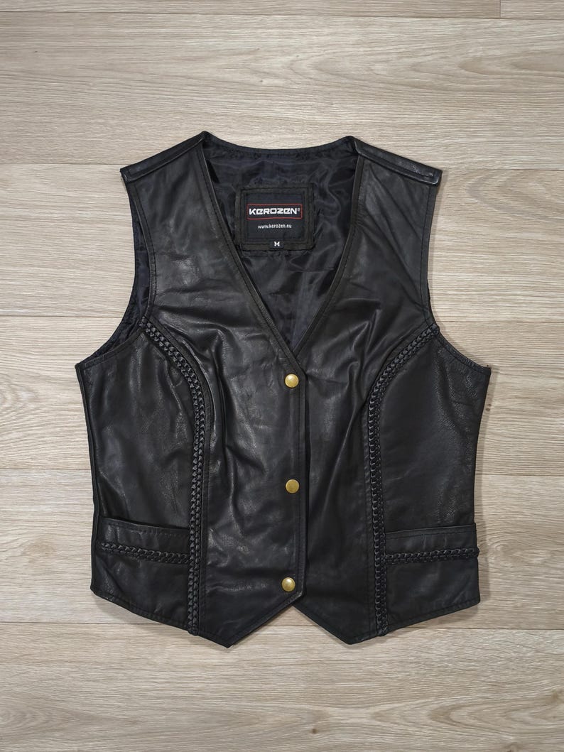 May include: Black leather vest with gold-colored buttons and braided trim. The vest has a V-neck and two front pockets. The brand name "KOROZAN" is visible on the label inside the vest.