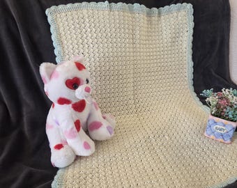 Cream colored crochet baby blanket with delicate scalloped edging in soft baby green.