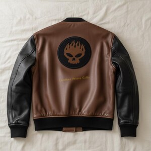 May include: Brown and black leather bomber jacket with a skull and flame logo on the back. The jacket has black sleeves and a black ribbed collar, cuffs, and hem. The text "Leather Prime Gifts" is below the logo.
