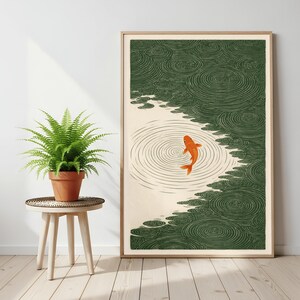 K&ouml;nnte beinhalten: Ein gerahmter Kunstdruck mit einem orangefarbenen Koi-Fisch, der in einem Teich schwimmt. Das Kunstwerk hat einen minimalistischen Stil mit beigem Hintergrund und gr&uuml;nen Wassermustern. Der Druck wird in einem hellen Holzrahmen angezeigt.