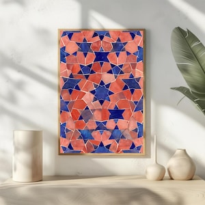May include: A framed print featuring a geometric pattern of red, blue, and pink shapes. The design includes star-like figures and irregular polygons, creating a mosaic effect. The artwork is displayed on a light-colored surface.