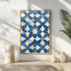 May include: A framed print with a mosaic pattern in blue, white, and beige. The geometric design features star and diamond shapes. The artwork is displayed on a white wall, with a neutral-toned shelf and decorative vases in the foreground.