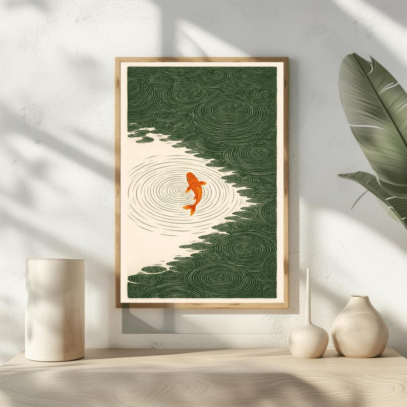 K&ouml;nnte beinhalten: Gerahmter Kunstdruck mit einem orangefarbenen Koi-Fisch, der in einem Teich schwimmt. Das Kunstwerk hat eine japanische &Auml;sthetik mit gr&uuml;nem Wasser und einem cremefarbenen Hintergrund. Der Fisch ist der Mittelpunkt, umgeben von konzentrischen Kreisen.