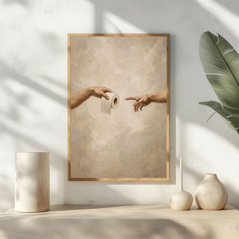 Puede incluir: Impresi&oacute;n art&iacute;stica enmarcada que parodia 'La Creaci&oacute;n de Ad&aacute;n' de Miguel &Aacute;ngel, con manos extendi&eacute;ndose hacia un rollo de papel higi&eacute;nico. La obra presenta una paleta de colores neutros y un marco de madera, ideal para la decoraci&oacute;n del ba&ntilde;o.