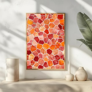 May include: A framed mosaic artwork featuring a vibrant pattern of irregular, geometric shapes in shades of red, orange, and pink. The artwork is displayed on a light-colored surface, with decorative vases and a plant in the background.