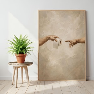 Puede incluir: Una impresi&oacute;n enmarcada que presenta una parodia de 'La Creaci&oacute;n de Ad&aacute;n' de Miguel &Aacute;ngel, con una mano ofreciendo un rollo de papel higi&eacute;nico. La obra de arte tiene un tono sepia y el marco es de madera.