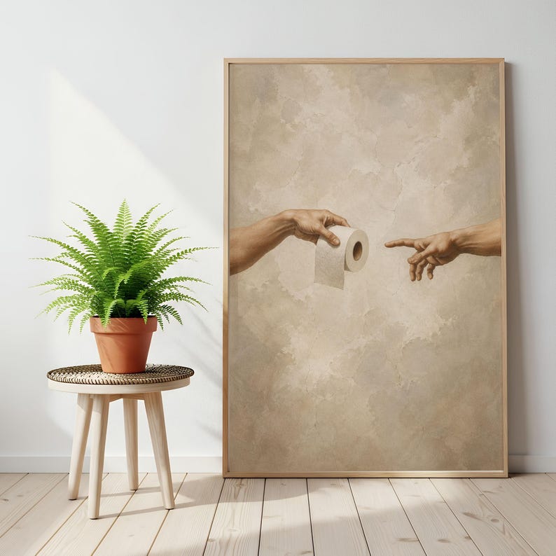 Puede incluir: Una impresi&oacute;n enmarcada que presenta una parodia de 'La Creaci&oacute;n de Ad&aacute;n' de Miguel &Aacute;ngel, con una mano ofreciendo un rollo de papel higi&eacute;nico. La obra de arte tiene un tono sepia y el marco es de madera.