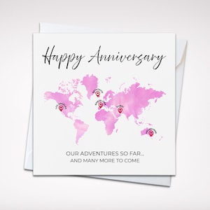 May include: A square greeting card featuring the text Happy Anniversary in black script. A pink watercolour world map is centred with red location pins labelled Los Angeles, Reykjavik, Barcelona, Dubai, and Melbourne. Text reads OUR ADVENTURES SO FAR... AND MANY MORE TO COME.