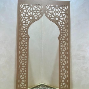 Peut inclure: Une arche décorative en bois marron avec des découpes géométriques complexes. L'arche présente un motif central en arc brisé et est flanquée de deux panneaux verticaux avec des motifs répétitifs d'étoiles et de fleurs. L'arche est placée dans un coin, avec un tapis à motifs visible en dessous.
