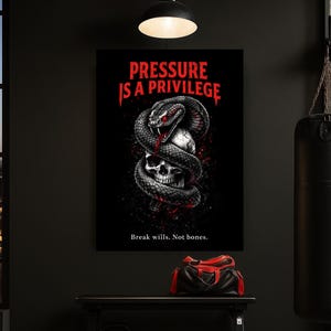 Könnte beinhalten: Schwarze Wandkunst mit einem Totenkopf, der von einer Schlange umschlungen wird, mit dem Text "PRESSURE IS A PRIVILEGE" in Rot. Darunter ist der Satz "Break wills. Not bones." in Weiß gedruckt. Das Kunstwerk wird in einem dunklen Raum ausgestellt.