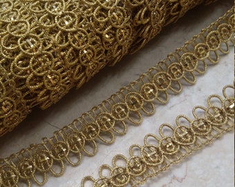 May include: Gold metallic trim with a delicate, intricate design. The trim is made of small, looped circles that create a delicate, airy look.