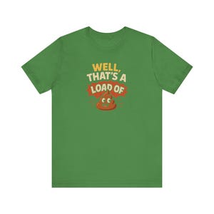 Può includere: T-shirt verde con la scritta "Well, that's a load of" sopra un'emoji a forma di cacca dei cartoni animati. Il testo è giallo e rosso, e la grafica è marrone. Una maglietta casual e umoristica.