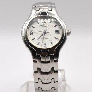 May include: A silver Rotary quartz watch with a white face, black numerals, and a date display. The watch has a silver bracelet strap and is displayed on a clear stand. The watch face reads 'Rotary'.