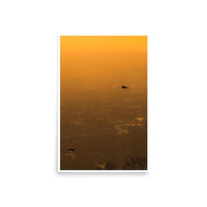 May include: A vertical print showing a warm, golden-orange sunset over a distant landscape. Two dark silhouettes of birds are in flight. The scene evokes a sense of peace and tranquility.
