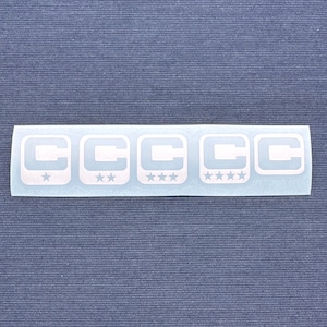 May include: A white sticker with the letters "C" repeated five times, each within a square. Each square contains a star, with the number of stars increasing from one to four.