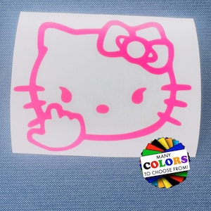 May include: A bright pink vinyl decal featuring the outline of a cartoon cat character with a bow on its head, shown making an obscene hand gesture. A small circular graphic in the corner displays a fan of various colors with the text MANY COLORS TO CHOOSE FROM!