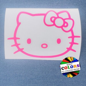 May include: A white rectangular decal featuring a bright pink outline of a cat character with a bow on its head. In the bottom right corner, there is a circular graphic with various colored segments and the text MANY COLORS TO CHOOSE FROM!