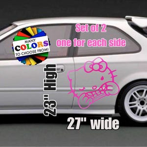 May include: A set of two pink vinyl decals featuring a cartoon character with a bow, applied to the side of a silver car. The text reads Set of 2 one for each side, MANY COLORS TO CHOOSE FROM!, 23" High, and 27" wide, indicating the dimensions.