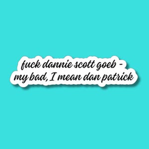May include: A white die-cut sticker featuring black cursive text that reads: fuck dannie scott goeb - my bad, I mean dan patrick. The sticker has a clean white border and is presented against a solid, bright turquoise background.