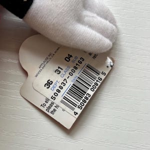 May include: A white plush hand with a black cuff, with a heart-shaped tag attached. The tag has text, including "APPLAUSE INC." and a barcode with the number "508837-008163".