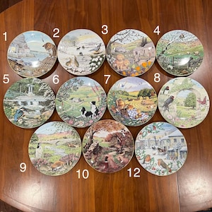 May include: A set of twelve decorative plates, each depicting a different rural scene. The plates feature illustrations of animals, landscapes, and buildings, with detailed artwork and bright colours. The plates are displayed on a wooden surface.