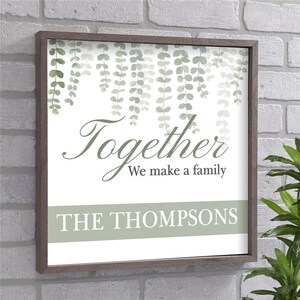 May include: A white framed wall sign with a green leafy design and the text "Together We make a family THE THOMPSONS".