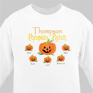 May include: White long-sleeve shirt with a pumpkin patch design. The text "Thompson Pumpkin Patch" is printed in yellow. There are six orange pumpkins with jack-o-lantern faces. The pumpkins are labeled "Dad", "Mom", "Kate", "Jack", and "Rose Lee".