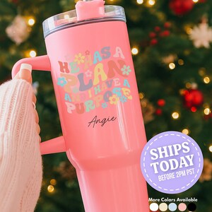 May include: A pink tumbler with a handle and a straw. The tumbler has the text "He Has A Plan And I Have A Purpose" in colorful letters and flowers. The name "Angie" is written below the text.