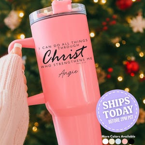 Może przedstawiać: Różowy kubek z uchwytem i przezroczystą pokrywką. Na kubku znajduje się napis "I CAN DO ALL THINGS THROUGH Christ WHO STRENGTHENS ME" oraz imię "Angie" czarną czcionką. Naklejka głosi "SHIPS TODAY".