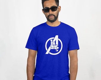 May include: Royal blue t-shirt with a white graphic that combines the letter "A" with the Los Angeles Dodgers logo. The design is inside a white circle. The shirt is short-sleeved and made of a soft material.