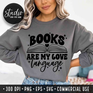 May include: A gray sweatshirt with the text "BOOKS ARE MY LOVE LANGUAGE" in black. The text is in a retro font with a stylized open book graphic and a heart above the book.