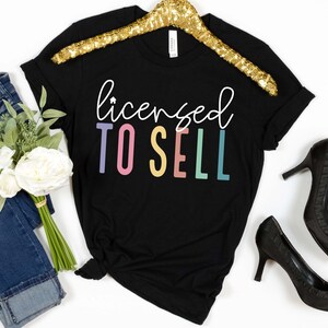 May include: Black t-shirt with the text "licensed to sell" in rainbow colors.