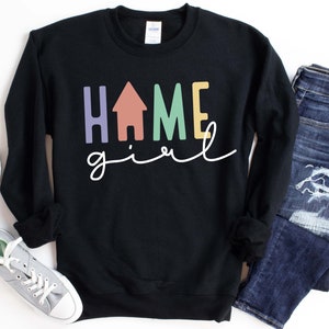 May include: Black sweatshirt with the text "home girl" in colorful letters, including a house icon in the middle of the word "home".