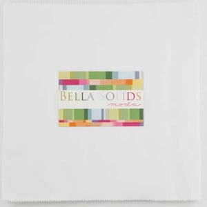May include: A square stack of white fabric squares with pinked edges. A rectangular label is centered on the stack, featuring horizontal stripes of various colors and the text Bella Solids moda printed in a mix of serif and script fonts.