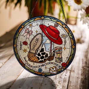 May include: A circular stained glass suncatcher featuring a red hat, a cow-print cowboy boot with the number 13, and a boot sole labelled TAYLOR. It includes blocks with letters T, S, and a heart, plus the text I KNEW IT I KNEW YOU.