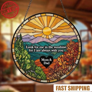 May include: A round stained glass window with a landscape scene. The design features a sun, mountains, trees, and the text "Look for me in the sunshine, for I am always with you." A heart shape with "Mom & Dad" is in the center.