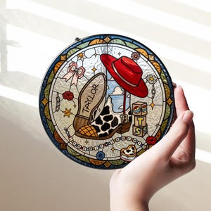 May include: A circular stained glass suncatcher featuring a cow-print cowboy boot with the name TAYLOR, a red hat, and blocks with the letters T, S, and the number 13. The design includes a pink bow, flowers, and the text I KNEW IT Y I KNEW Y O.