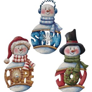 Könnte beinhalten: Drei dekorative Schneemann-Ornamente mit bemalten Details. Ein Schneemann trägt eine rote Mütze und einen Schal mit dem Wort HOPE, einer blaue Ohrenschützer und einen Schal mit SNOW, und einer einen schwarzen Zylinder und einen grünen Schal mit dem Wort JOY.
