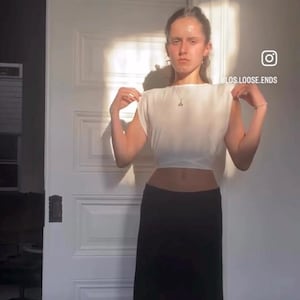 Puede incluir: Una camiseta blanca sin mangas y una falda larga negra. La camiseta tiene cuello barco y un diseño sencillo. La falda es de cintura alta y llega hasta los tobillos. El nombre de Instagram @BLOS.LOOSE.ENDS es visible.