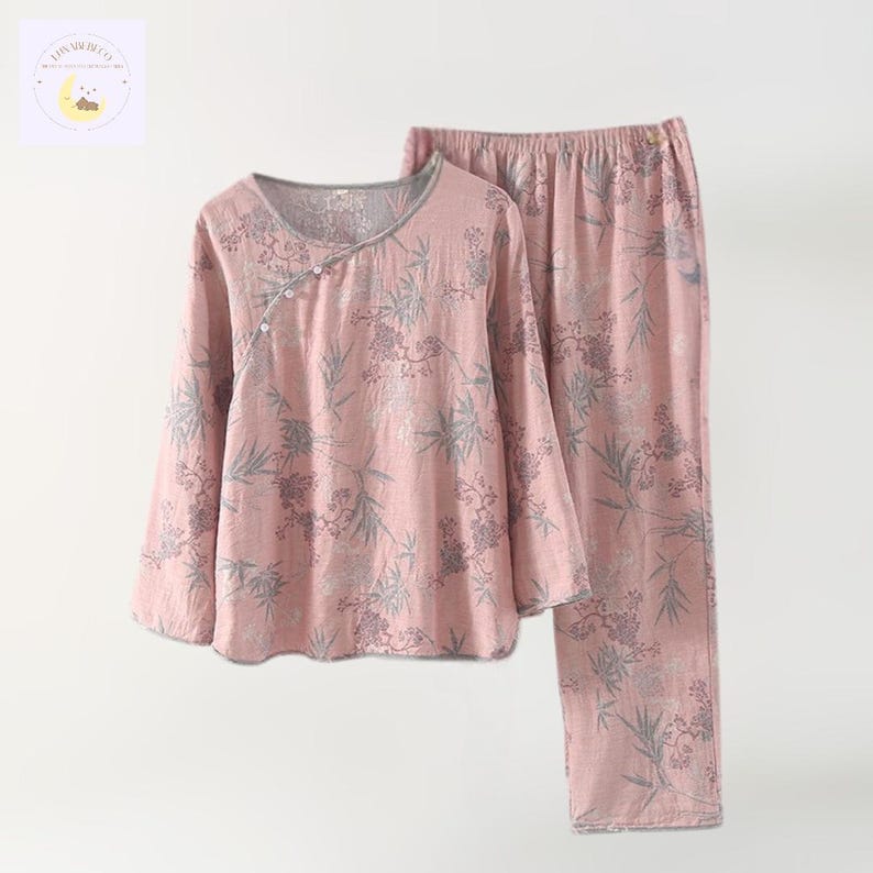 May include: Pink pajama set with a floral pattern. The long-sleeved top has a V-neck and button closure. The pants are straight-legged. The set is made of a soft, lightweight fabric, perfect for lounging or sleeping.