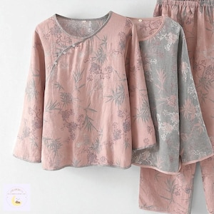 Puede incluir: Conjuntos de pijama de dos piezas en rosa y gris. Las partes de arriba tienen mangas largas y estampados florales. La parte de arriba rosa tiene un escote cruzado con cierres de botón. La parte de arriba gris tiene cuello redondo. Los pantalones de pijama son rosas con diseño floral a juego. Medidas en cm.