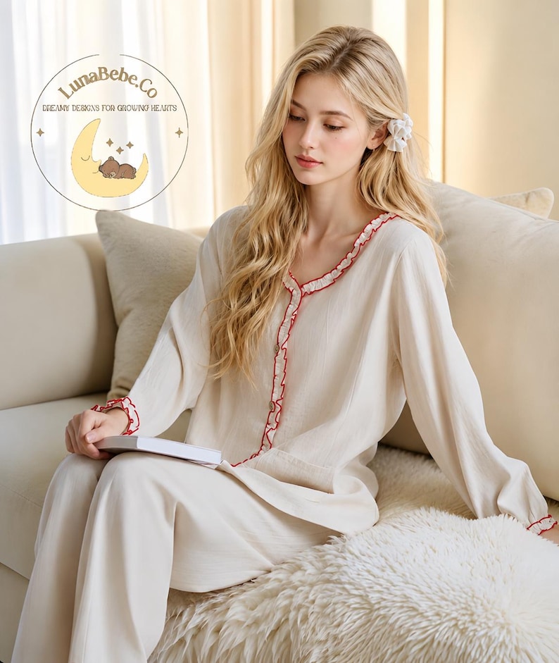 May include: Cream-colored pajama set with red ruffle trim. The long-sleeved top and pants are made of a soft fabric. The image includes the LunaBebe.Co logo with the text "Dreamy Designs for Growing Hearts".